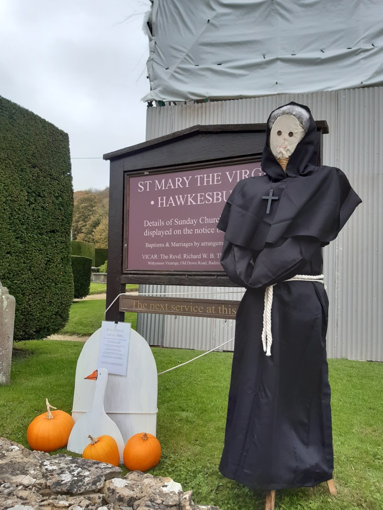 photo of scarecrow with wooden goose and pumpkins outside church